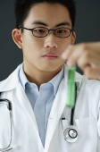Doctor holding test tube filled with green liquid - Asia Images Group
