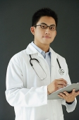 Doctor holding clipboard, looking at camera - Asia Images Group