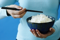 Woman holding bowl of rice and chopstick - Asia Images Group
