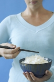 Woman holding bowl of rice and chopstick, cropped image - Asia Images Group