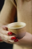 Close up of womans hands holding tea cup - Asia Images Group