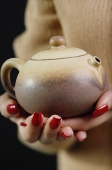 Close up of womans hands holding tea pot - Asia Images Group