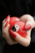Womans hands with red nail polish, holding Yin Yang balls, close-up - Asia Images Group