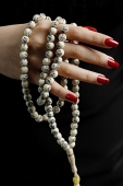 Womans hands with red nail polish, holding prayer beads - Asia Images Group