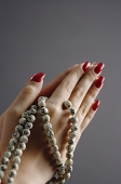 Womans hands in praying position with prayer beads - Asia Images Group