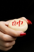 Womans hand holding one Chinese chess piece with Chinese script - Asia Images Group