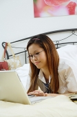 Girl lying on bed, using laptop - Asia Images Group