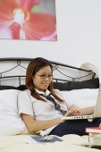 Girl sitting on bed, using laptop - Asia Images Group