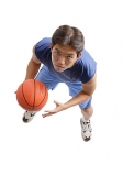Young man holding basketball, looking up at camera - Asia Images Group