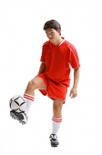 Young man in soccer uniform balancing soccer ball on leg - Asia Images Group