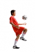 Young man in soccer uniform kneeing soccer ball - Asia Images Group