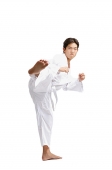 Young man practicing martial arts, kicking - Asia Images Group
