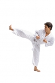 Young man practicing martial arts uniform, kicking with one leg - Asia Images Group