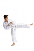 Young man wearing martial arts uniform, standing on one leg - Asia Images Group