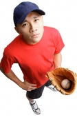 Young man holding baseball glove and ball, hand on hip - Asia Images Group