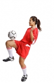 Young woman in soccer uniform, balancing ball on knee - Asia Images Group