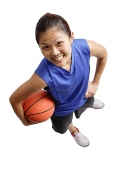 Young woman holding basketball, smiling at camera - Asia Images Group