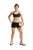 Young woman standing with hand on hip, holding volleyball - Asia Images Group