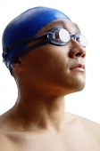 Young man wearing swimming cap and goggles, head shot - Asia Images Group