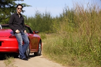 Man leaning on red sports car - Asia Images Group