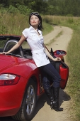 Woman leaning on red sports car, portrait - Asia Images Group