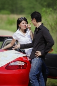 Couple with red sports car, arguing - Asia Images Group