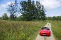 Red sports car on rural road - Asia Images Group