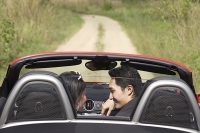 Couple in convertible sports car, looking at each other, rear view - Asia Images Group