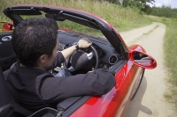 Man driving red convertible sports car - Asia Images Group