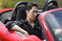 Man driving red convertible car - Asia Images Group