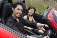 Couple sitting in convertible sports car, smiling at camera - Asia Images Group