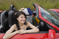 Woman sitting in convertible car, shopping bags next to her, smiling at camera - Asia Images Group