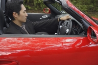 Man driving red convertible car - Asia Images Group