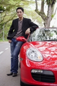 Man standing next to red sports car - Asia Images Group