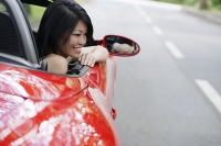Woman sitting in red sports car - Asia Images Group
