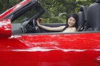 Woman driving red sports car, looking at camera - Asia Images Group