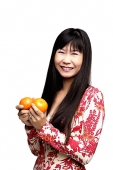 Woman with long straight hair, holding two oranges - Asia Images Group