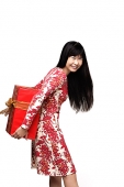 Woman with long straight hair, holding gift wrapped box behind her, smiling - Asia Images Group