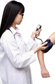 Female doctor checking blood pressure of patient - Asia Images Group
