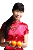Woman in Cheongsam, holding two oranges - Asia Images Group