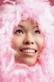 Woman with pink feathers around her face, looking up - Asia Images Group