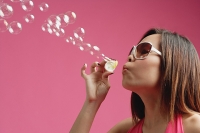 Woman wearing sunglasses, blowing bubbles - Asia Images Group