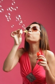 Woman dressed in pink, blowing bubbles - Asia Images Group