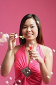 Woman dressed in pink, holding bubble wand - Asia Images Group