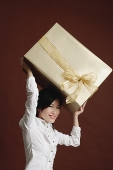 Woman lifting big gift wrapped box - Asia Images Group