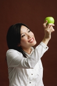 Woman looking at green apple - Asia Images Group