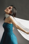 Woman wearing large sunglasses, tube top and scarf, arms outstretched - Asia Images Group