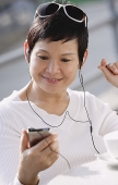 Mature woman listening to music from an MP3 player - Asia Images Group