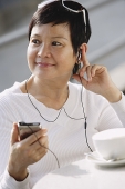 Woman listening to music from an MP3 player - Asia Images Group