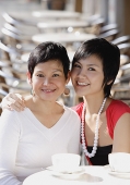 Mother and adult daughter in cafe, smiling at camera, portrait - Asia Images Group
